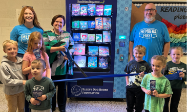 M1 team members and students from Freeland Learning Center stand by the book vending machine.